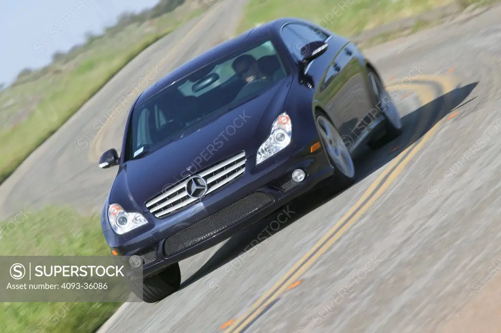 2006 AMG Mercedes Benz CLS55 cornering hard on a twisty rural road, front 3/4