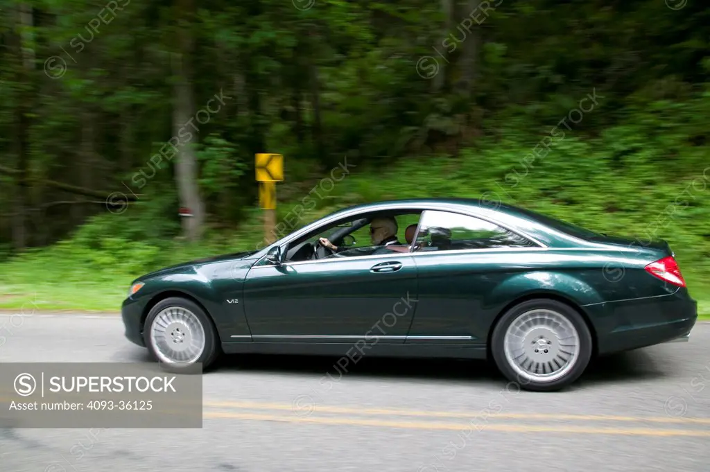 2007 Mercedes Benz CL600 driving on a rural tree lined road, side view