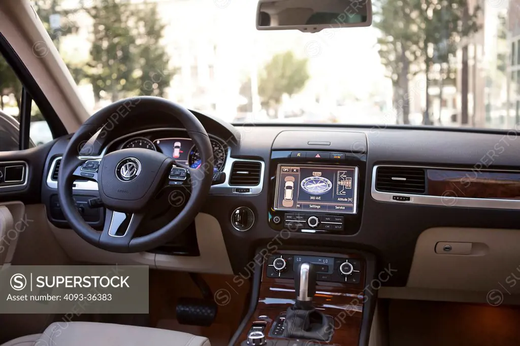 Interior view of a 2011 Volkswagen Touareg showing the steering wheel, instrument panel, center console, multi-function electronic display, GPS navigation and gear shift lever.
