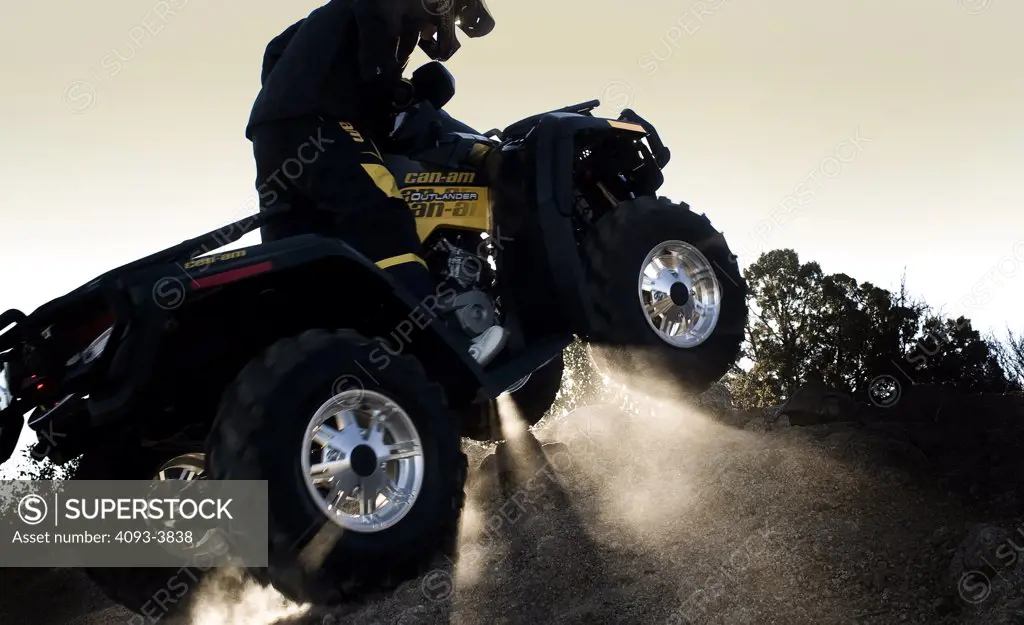 Can-Am ATV riding up hill with sunlight shining underneath