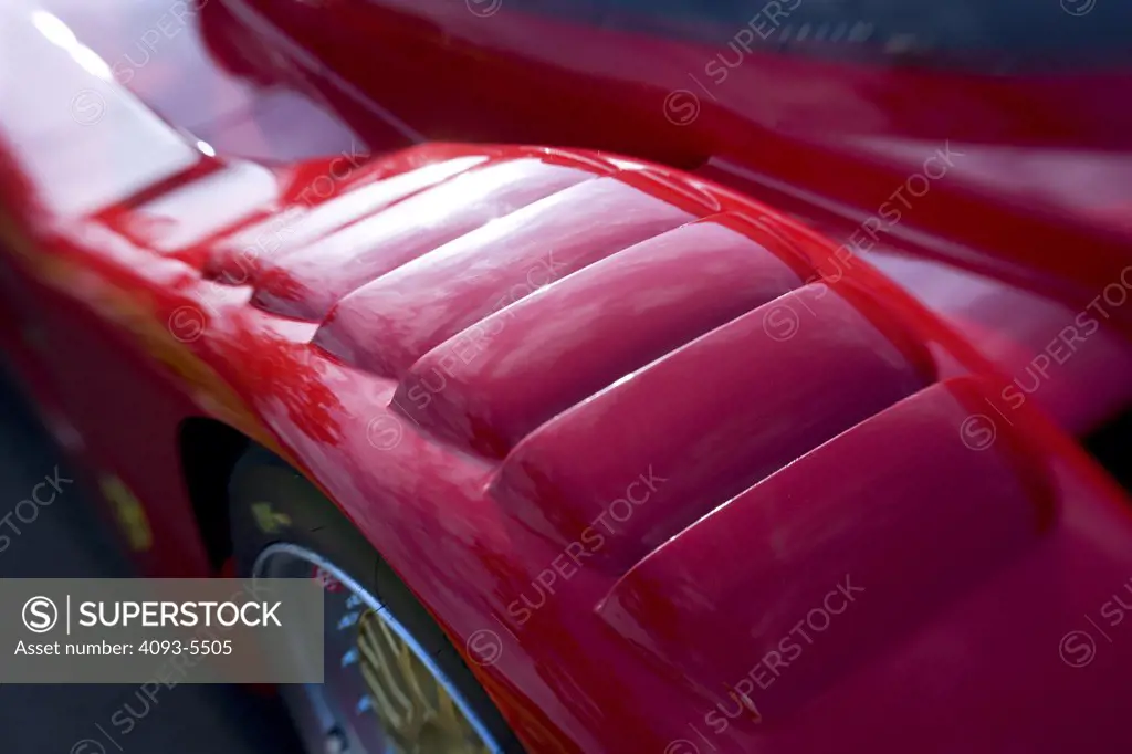 top of  a wheel well of a Ferrari during a car show with the edges blurred