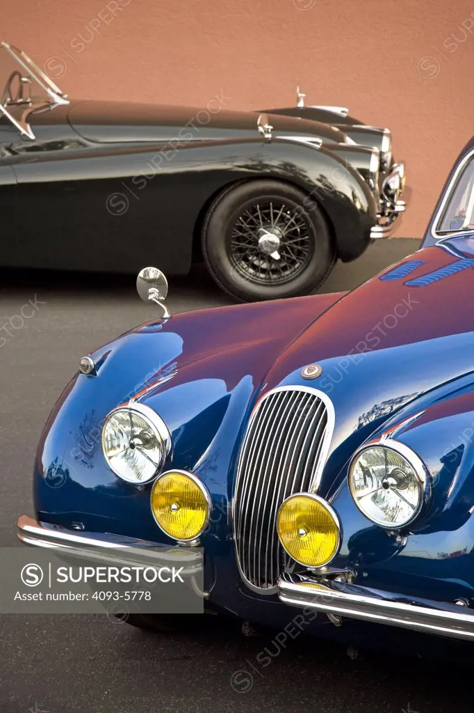 A 1953 Jaguar XK 120 coupe and 1950 Jaguar XK 120 roadster parked next to each other with a 3/4 front side and profile view.