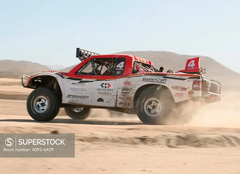 Baja racing truck custom modified vehicle racing in the dirt sand speeding by