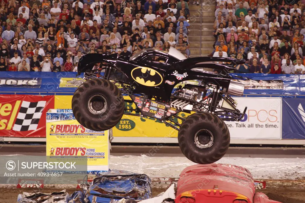 Batman Monster Truck jumping buses at a Monster Truck Rally in Raymond James Stadium, Tampa, FL. A monster truck is an automobile, typically a pickup truck, which has been modified or purposely built with extremely large wheels and suspension. Typically, a monster truck show involves the truck crushing smaller vehicles beneath its huge tires. These trucks can run up and over most man-made barriers, so they are equipped with remote shut-off switches, called the Remote Ignition Interuptor (RII), t