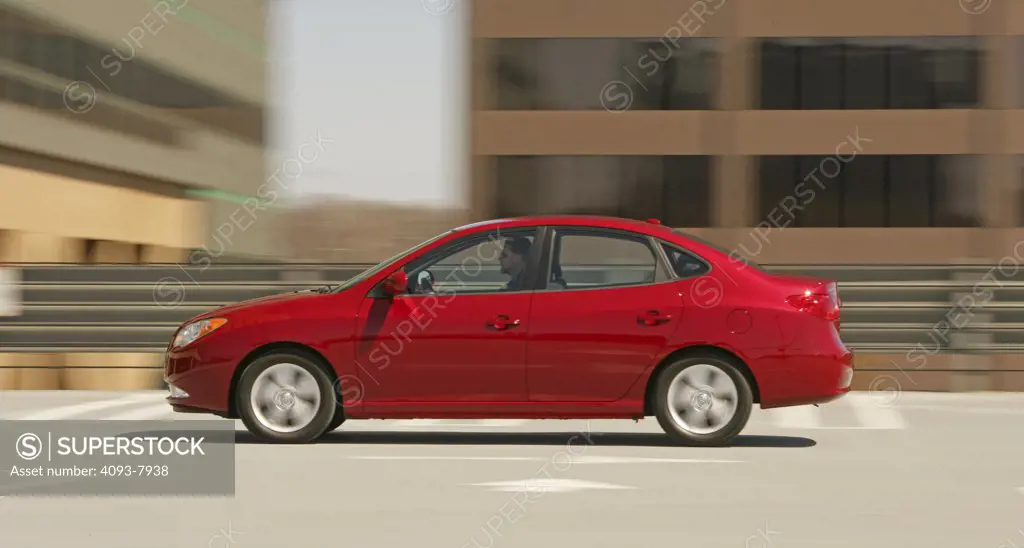 Profile action of a 2007 red Hyundai Elantra sedan. blur in roof top parking lot.