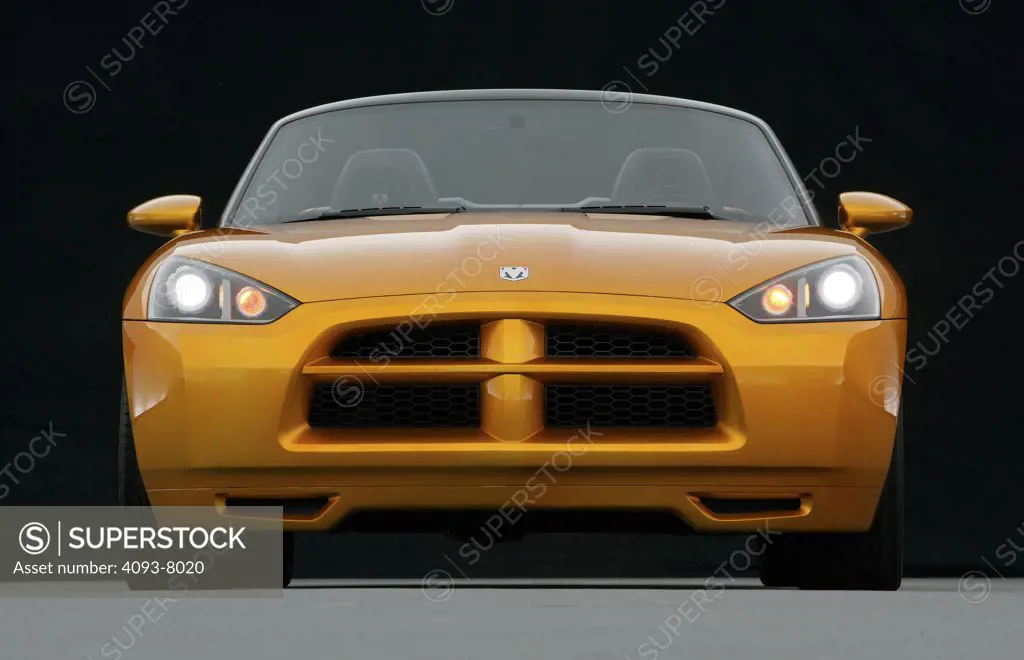 Straight on nose view of a Dodge Demon Convertible concept. Gold color inside parked viewing with backdrop