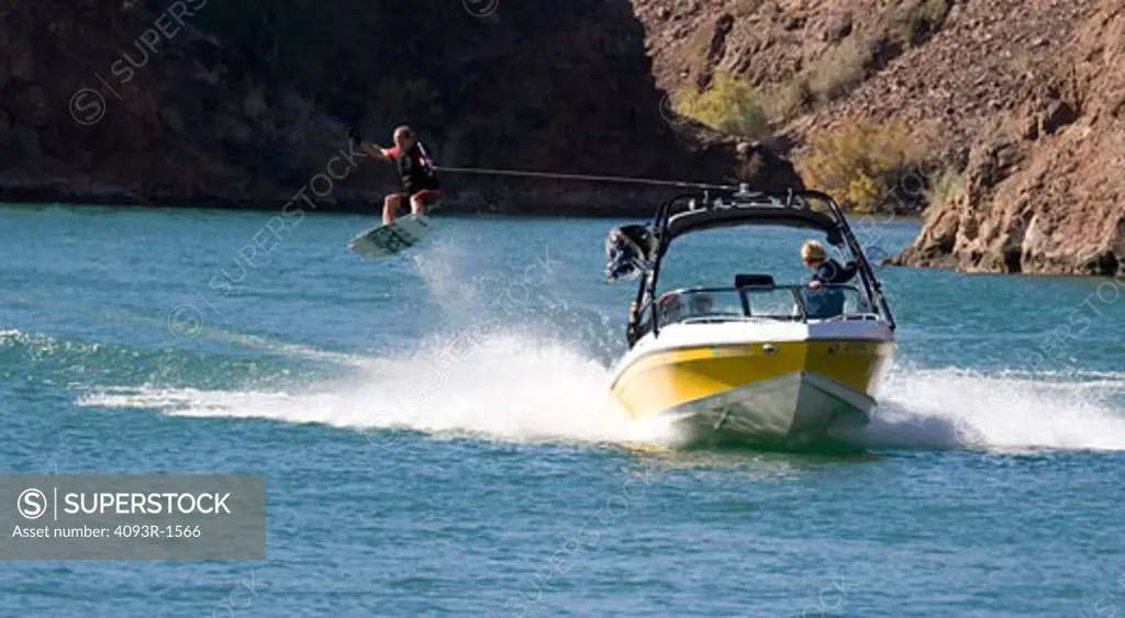Malibu wakesetter 21VLX on Lake Havasu, AZ pulling a wakeboarder who's jumping over the boat's wake.