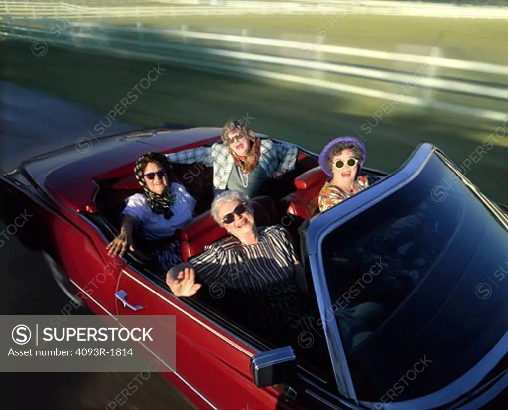 Four older ladies having fun out for a drive in a red 1975 Cadillac Eldorado convertible.