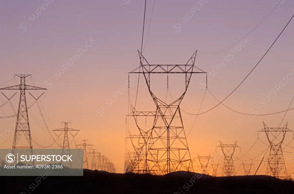 Power lines fading in the distance of hills during sunrise.