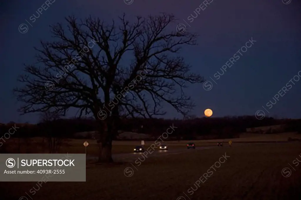 Cars on 2-lane road as the moon rises, Madison, Wisconsin