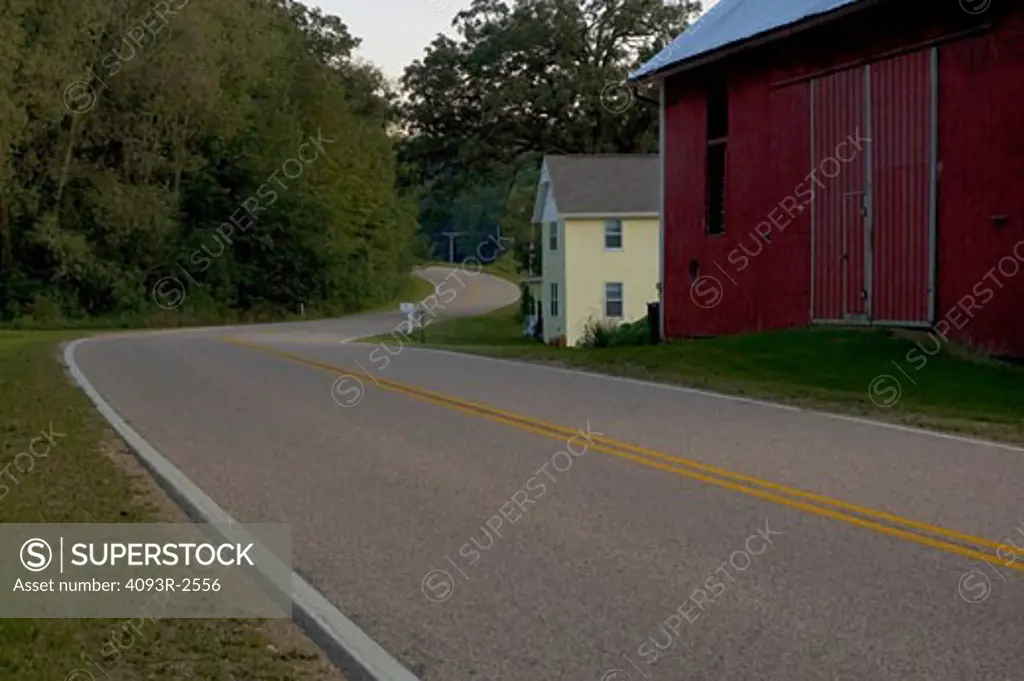 Curving rural road past farm buildings, southwest Wisconsin