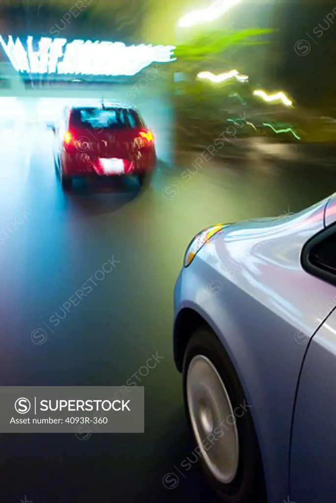 two cars following with motion blurrs through a garage