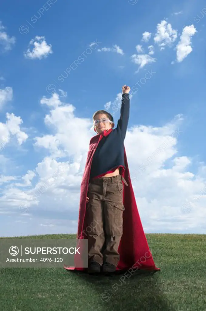 Boy imitating a super hero on a hill
