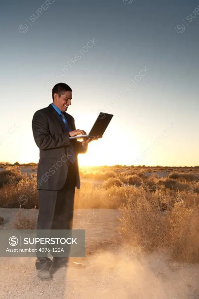 Businessman working on a laptop in desert