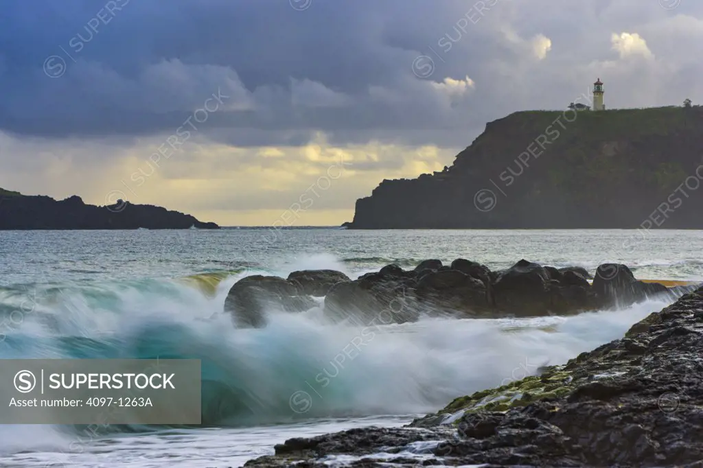 Waves breaking on beach with lighthouse in the background, Kilauea Lighthouse, Secret Beach, Kauai, Hawaii, USA