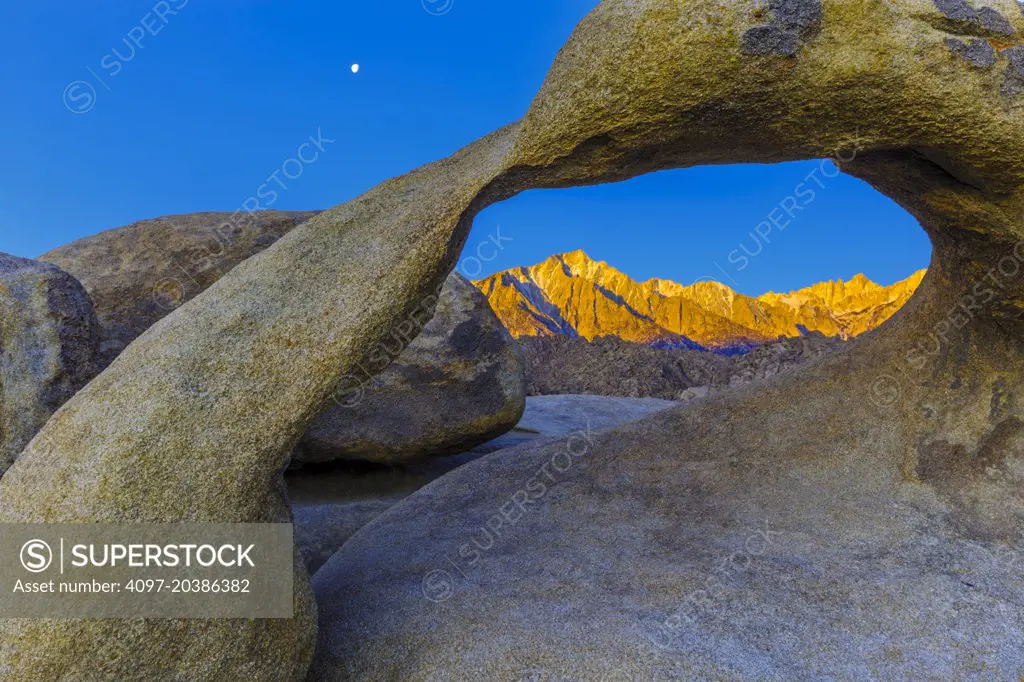 Mobius Arch in Alabama Hills at dawn with moon and Mount Whitney and Lone Pine, California