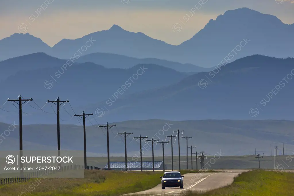 Car on road with mountains in the background, Rocky Mountains, Alberta, Canada