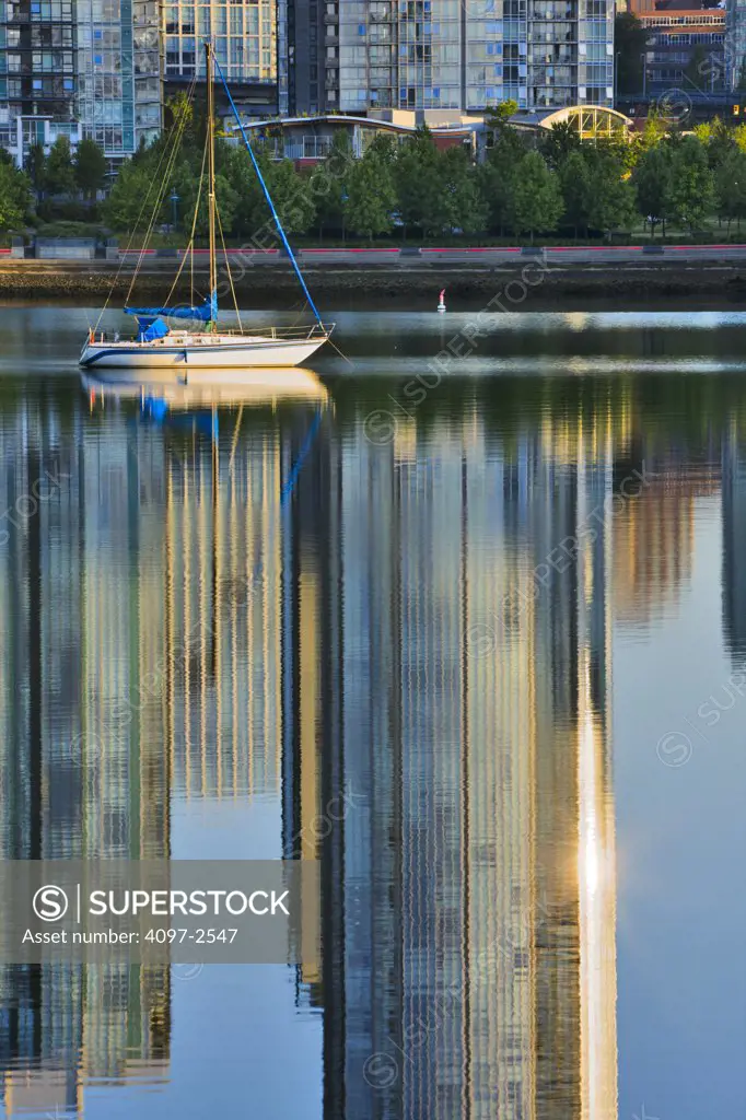 Sailboat with reflection of condominiums in creek, False Creek, Vancouver, British Columbia, Canada