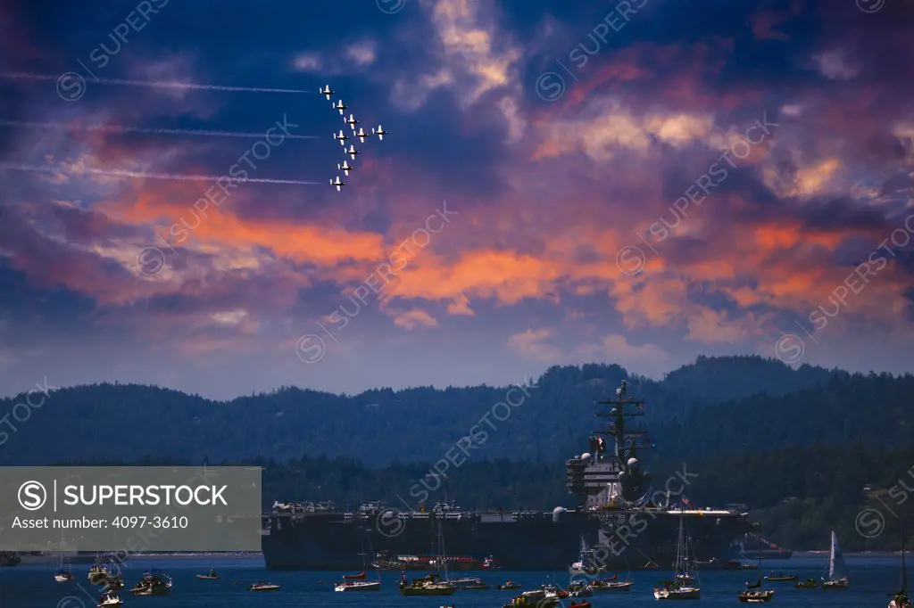 Aircraft carrier USS Ronald Reagan in a lake with Snowbirds fighter planes at flight in the sky, British Columbia, Canada