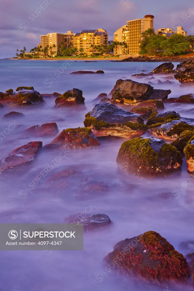 Rocks on the beach with buildings in the background, Kahana, Maui, Hawaii, USA