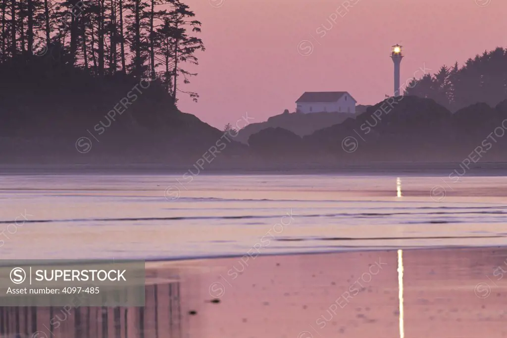 Beach at sunset with lighthouse in the background, Pacific Rim National Park Reserve, Vancouver Island, British Columbia, Canada