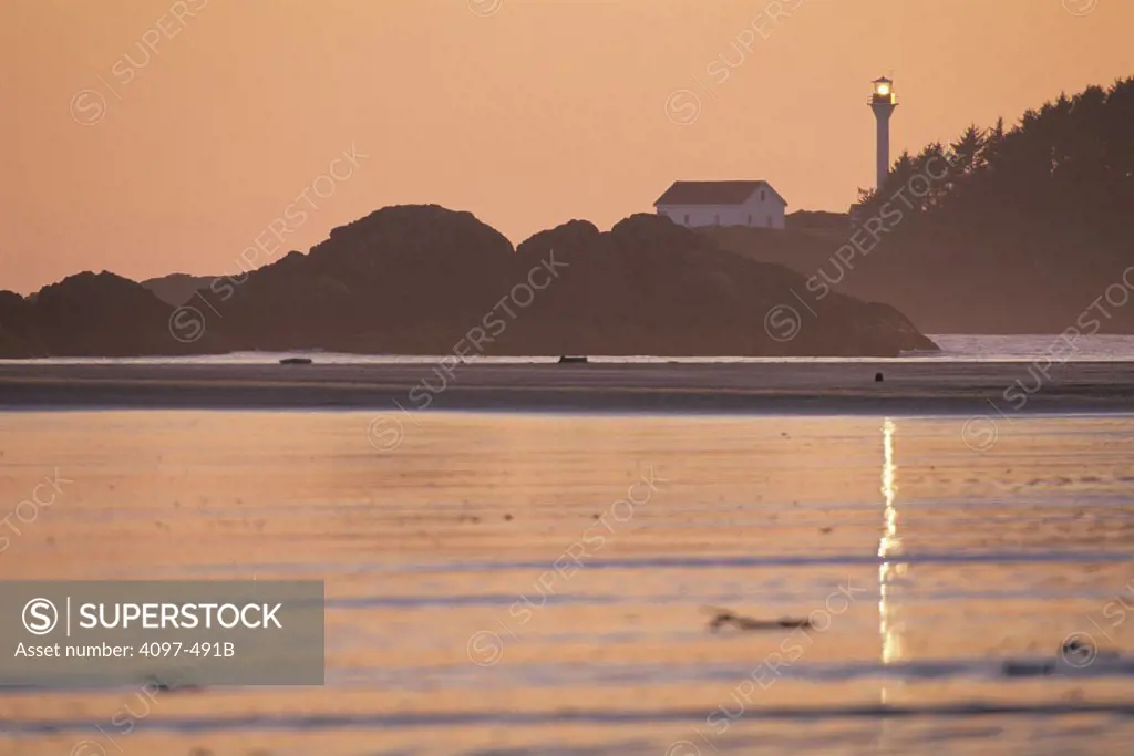 Beach at sunset with lighthouse in the background, Pacific Rim National Park Reserve, Vancouver Island, British Columbia, Canada