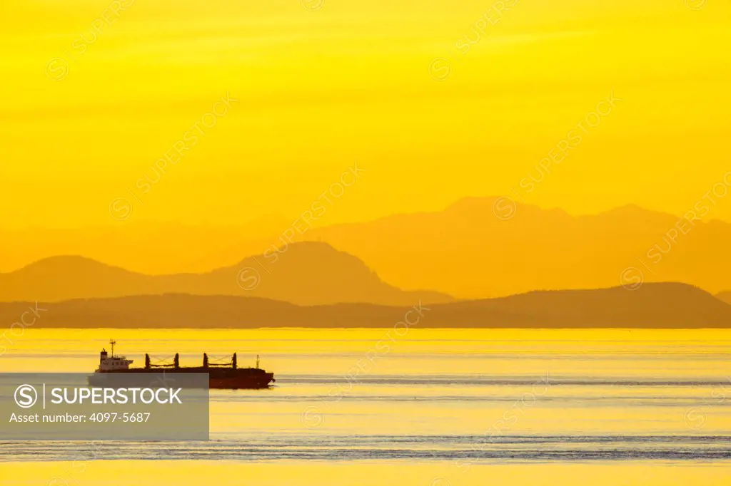 freighter in Stait of Jaun de Fuca with San Juan Islands in distance at dawn, seen from Victoria