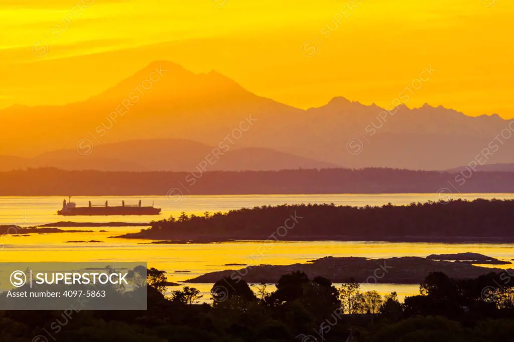 Canada, British Columbia, Vancouver Island, Freighter in Haro Strait with Mount Baker in distance at dawn