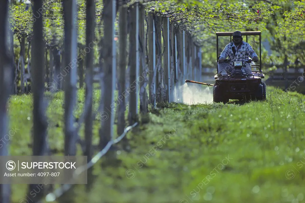 Farmer on a tractor spraying a field, Saanich Peninsula, Victoria, British Columbia, Canada