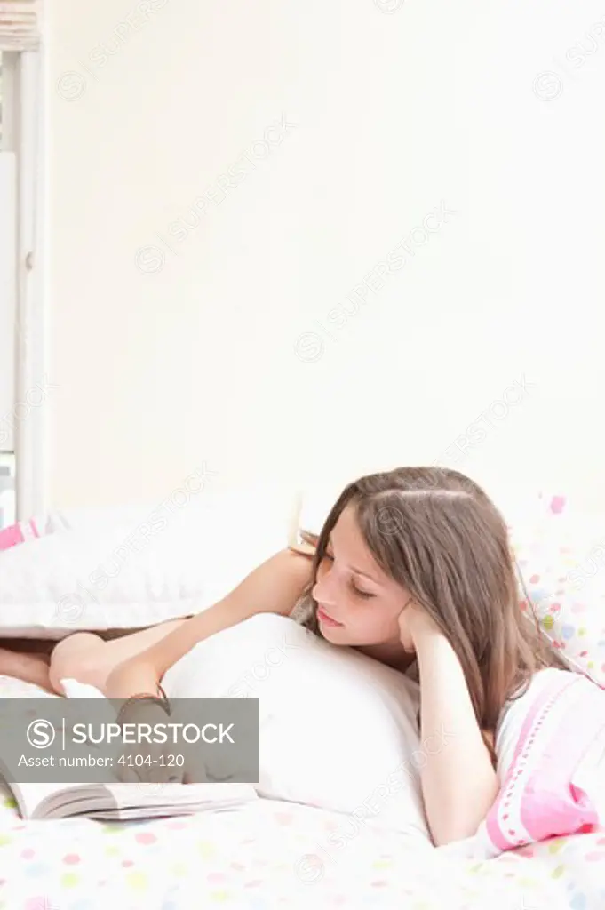 Teenage girl reading a book on the bed