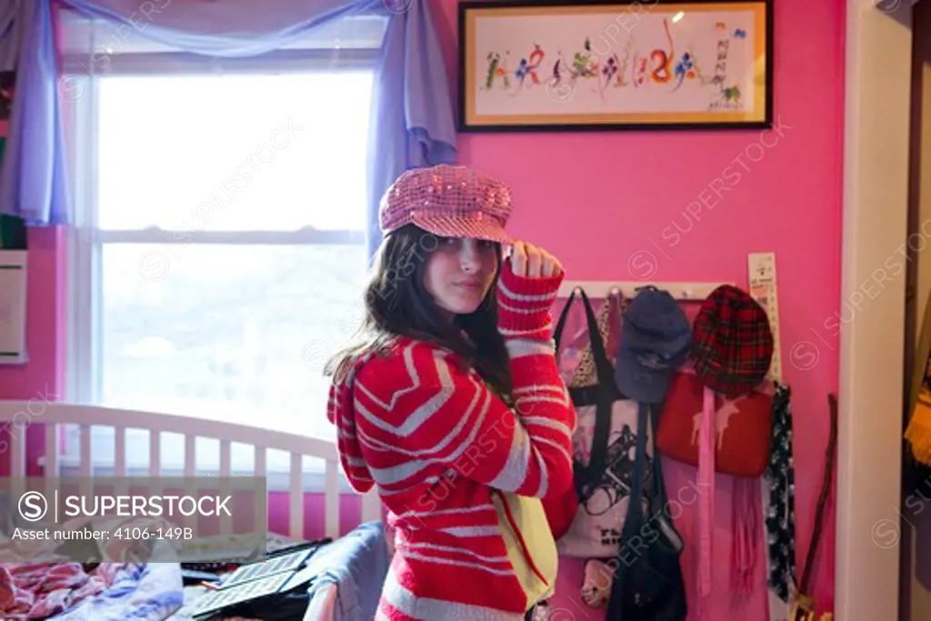 Teenage girl trying on sequined cap in a bedroom