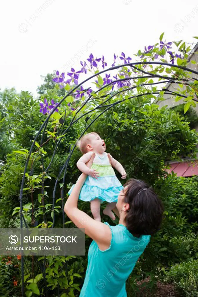 Mother playing with baby girl in garden