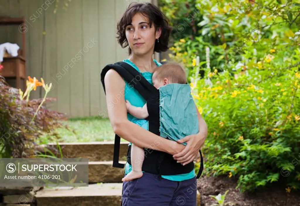 Mother carrying  baby girl outdoors
