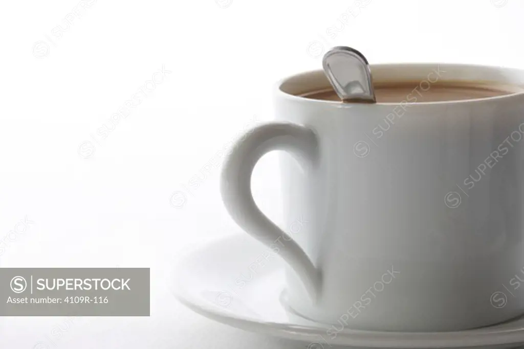Close-up of a cup of coffee with a saucer and stirrer spoon