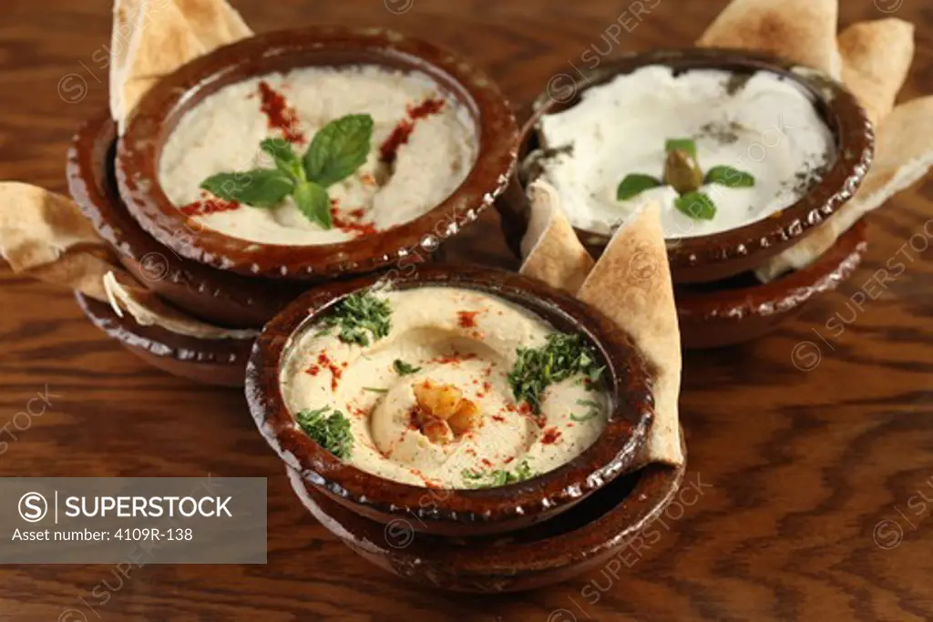 Three bowls of dips with pita slices