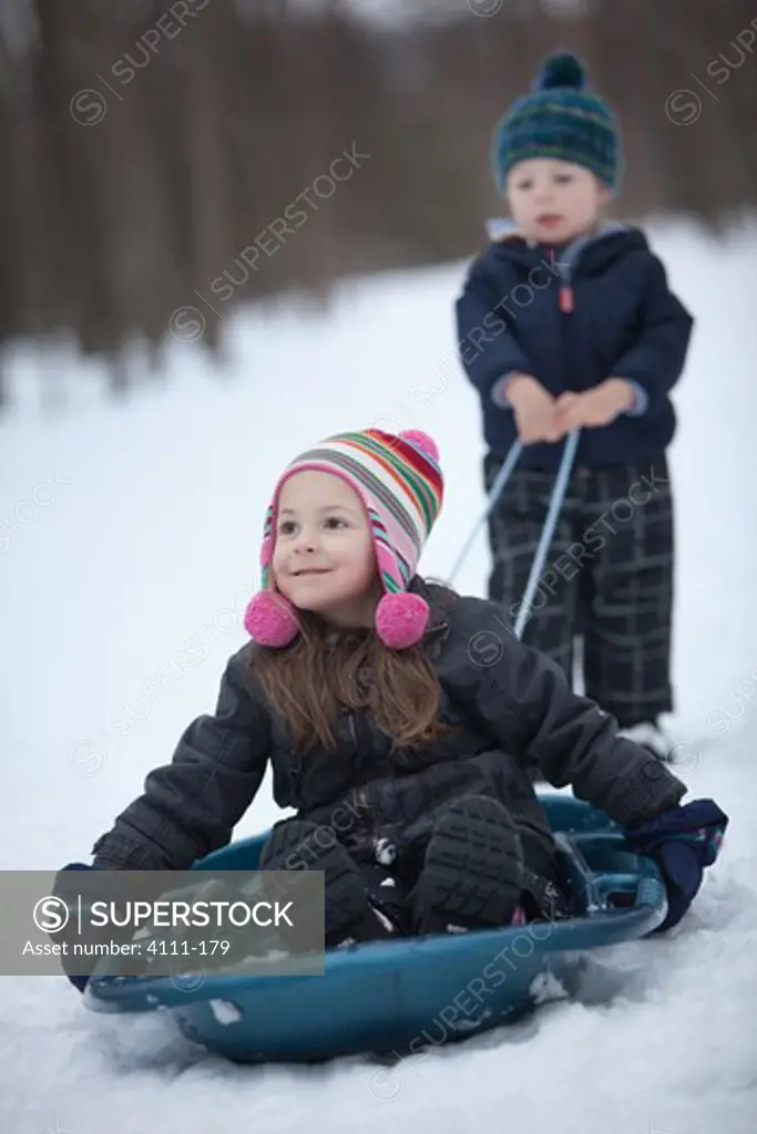 Boy pulling a girl sitting in sled, Traverse City, Grand Traverse County, Michigan, USA