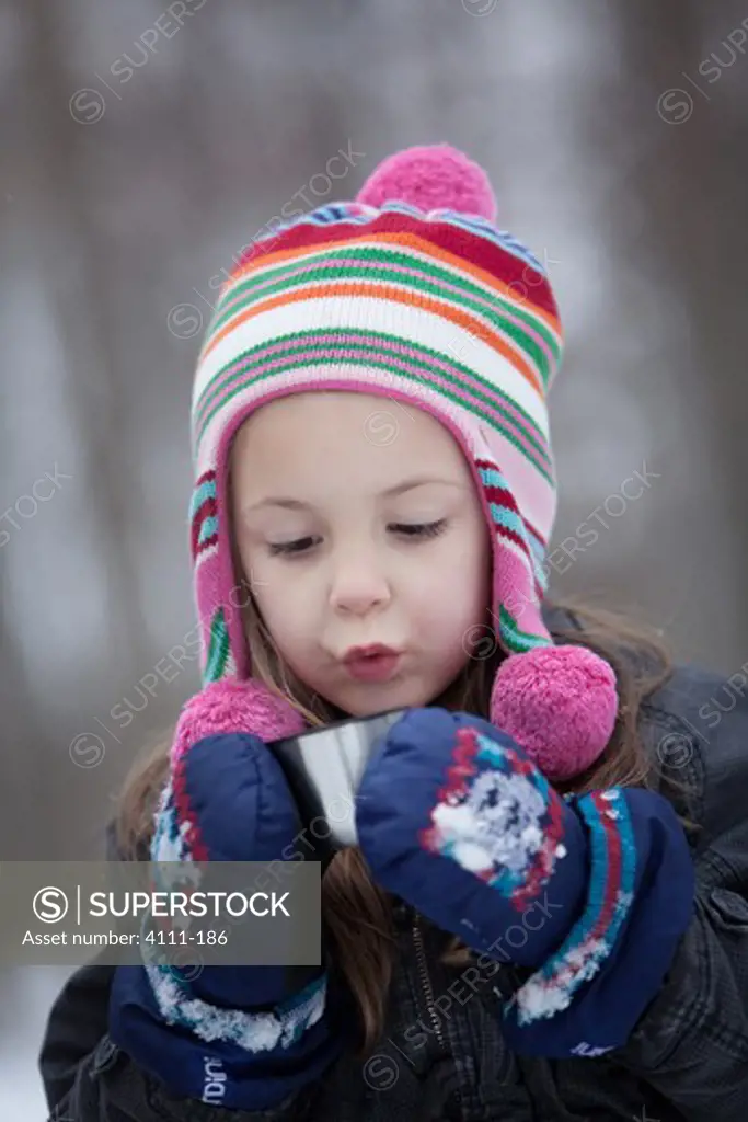 Girl drinking hot chocolate in snow, Traverse City, Grand Traverse County, Michigan, USA