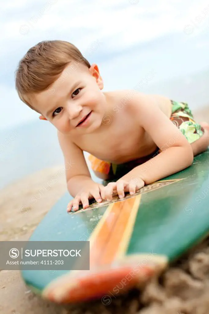 Boy lying on a surfboard on the beach, Glen Arbor, Leelanau County, Michigan, USA