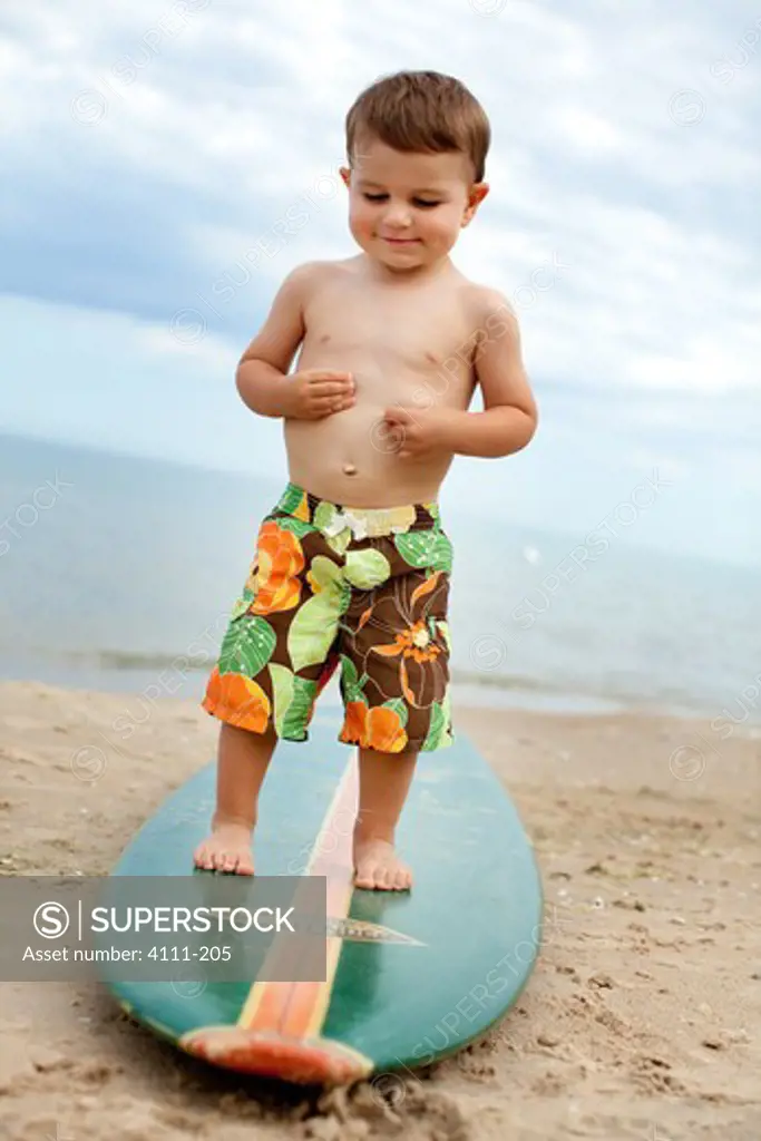 Boy standing on a surfboard on the beach, Glen Arbor, Leelanau County, Michigan, USA