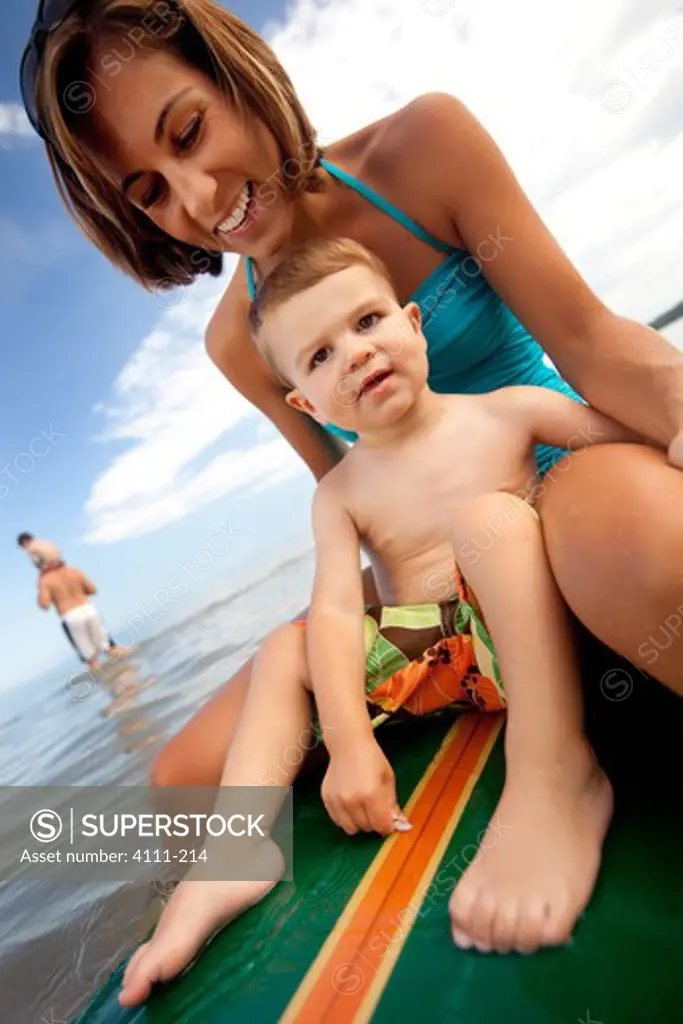 Woman with her baby boy sitting on a surfboard, Lake Michigan, Glen Arbor, Leelanau County, Michigan, USA
