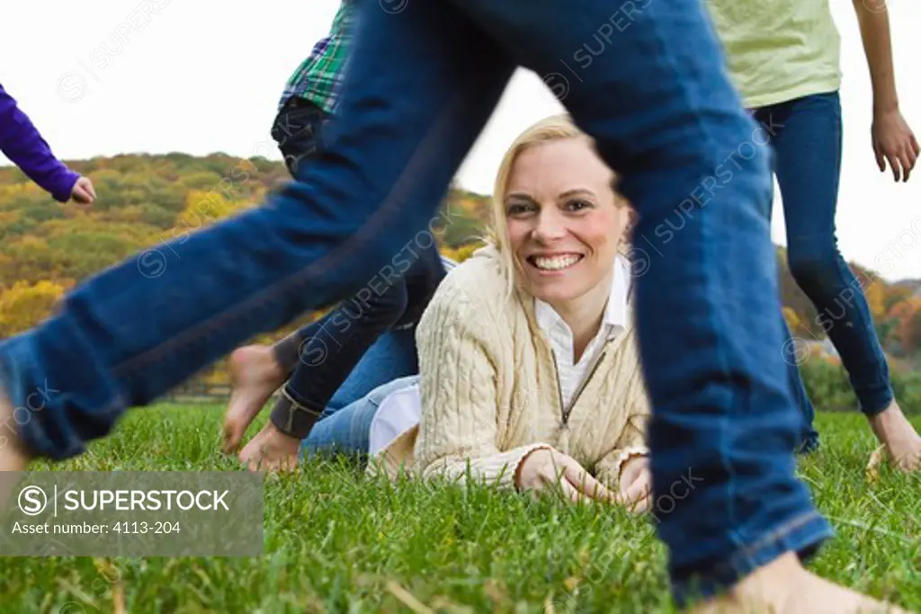 Portrait of woman lying on grass, people running around