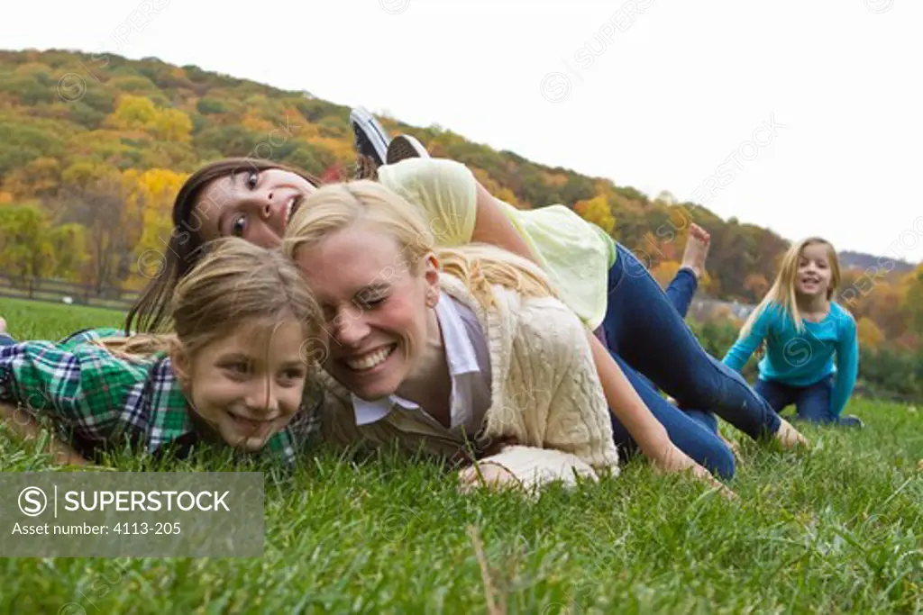 Mother playing with three daughters playing on grass
