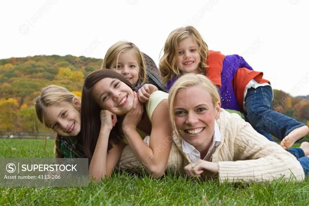 Portrait of mother with four daughters lying on grass