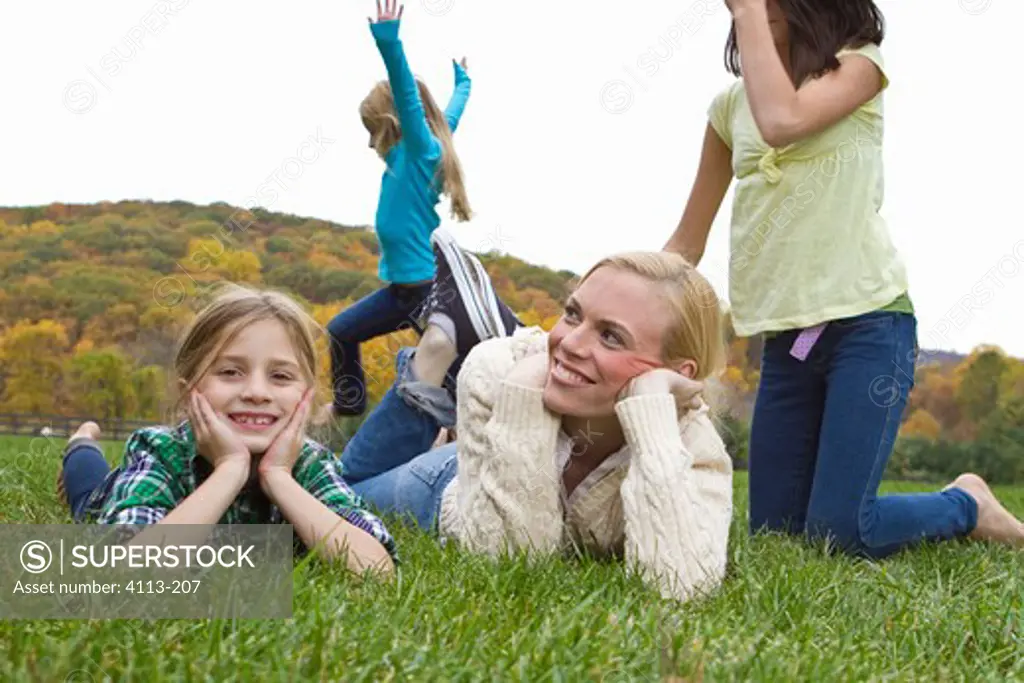 Mother playing with three daughters playing on grass