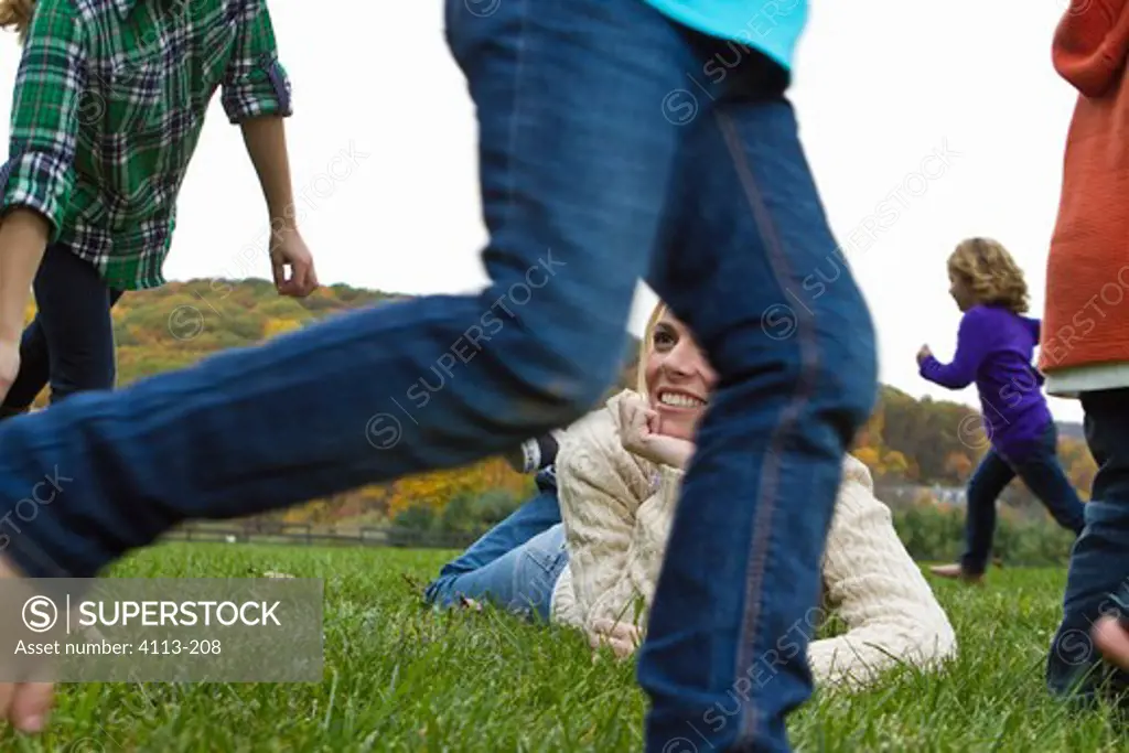 Woman lying on grass, children running around