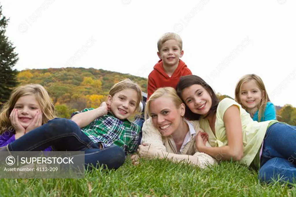 Portrait of mother with five children lying on grass