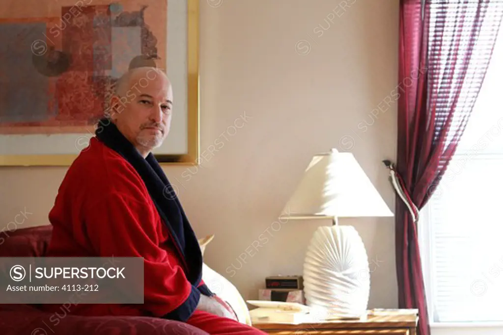 Mature man sitting on bed looking serious