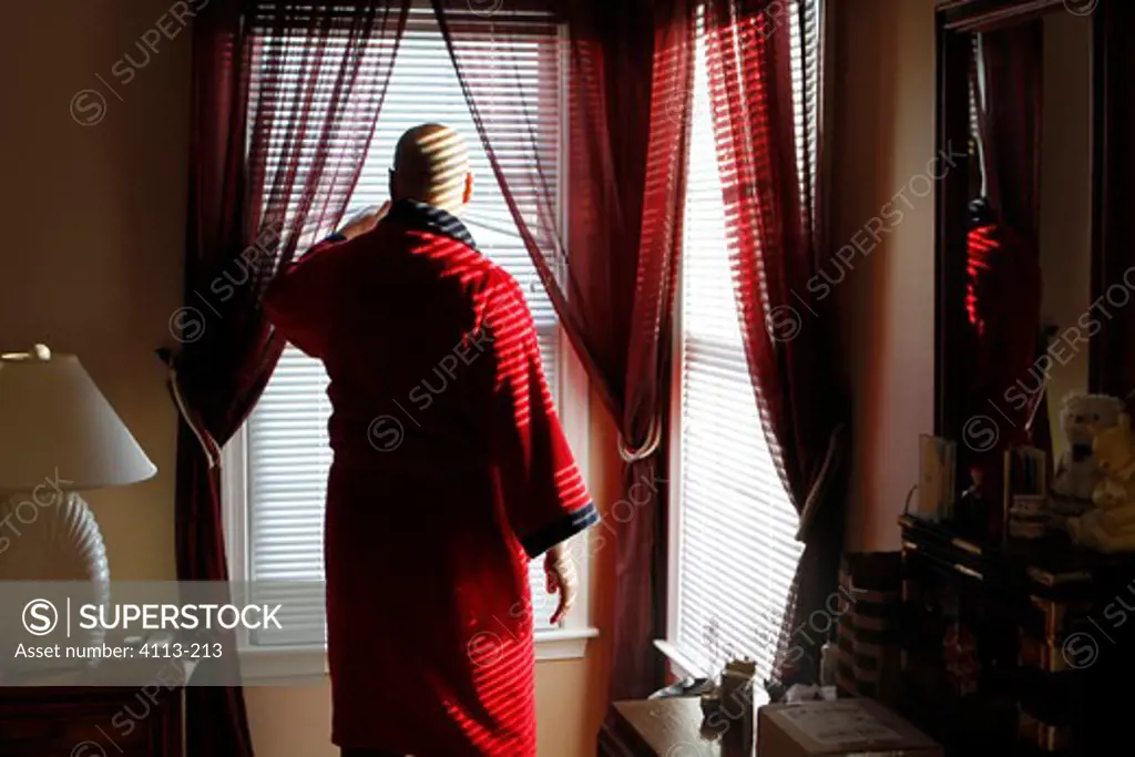 Mature man looking out of bedroom window