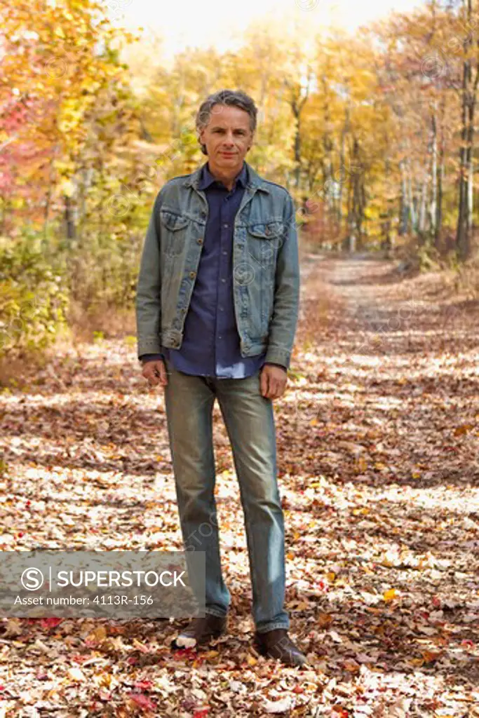 Portrait of man standing on Autumn forest track