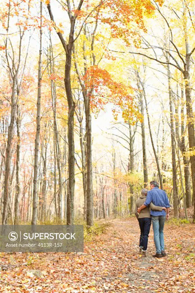 Rear view of mature couple walking on Autumn forest track